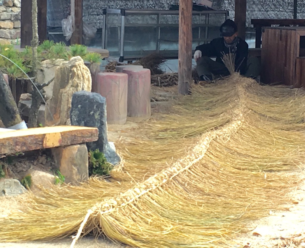 An old man weaving a straw roof in Hahoe.